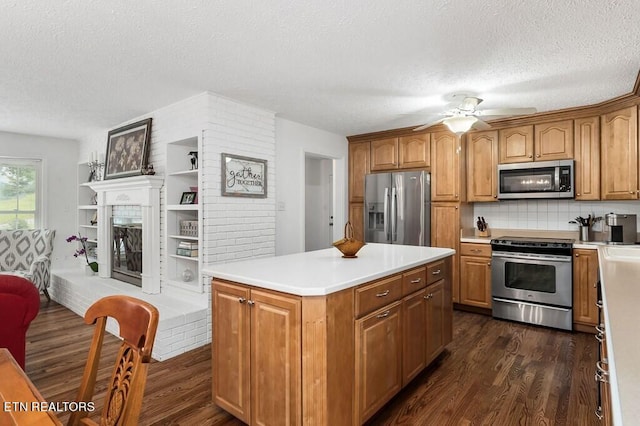 kitchen featuring a textured ceiling, a kitchen island, stainless steel appliances, dark hardwood / wood-style flooring, and ceiling fan