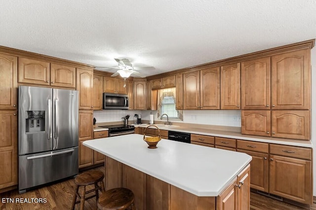 kitchen featuring dark hardwood / wood-style floors, black appliances, a center island, and ceiling fan