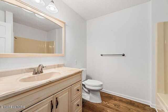 bathroom featuring wood-type flooring, a textured ceiling, vanity, and toilet