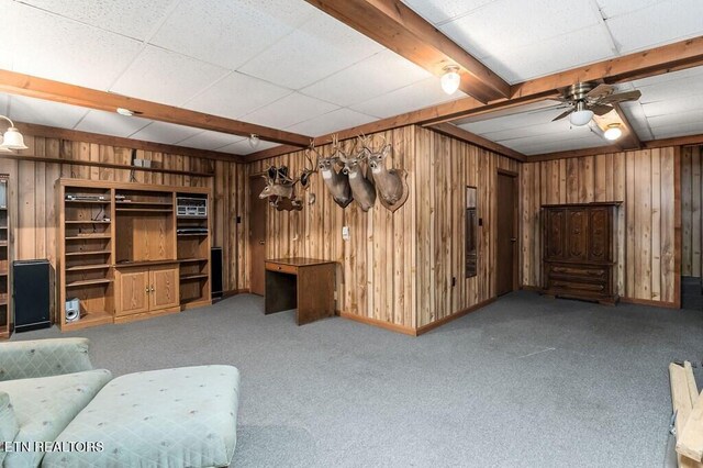 interior space featuring wooden walls, carpet, ceiling fan, and beamed ceiling