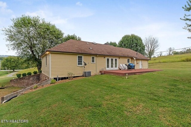 back of house with cooling unit, a wooden deck, and a yard