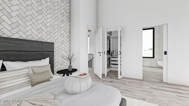 bedroom with tile walls, ensuite bath, a high ceiling, and light hardwood / wood-style flooring