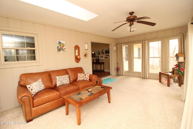 carpeted living room featuring ceiling fan and a skylight