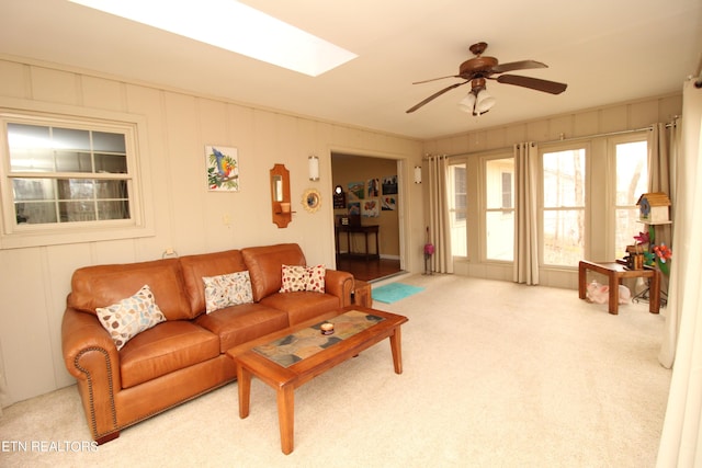 living area with a ceiling fan, a skylight, and carpet