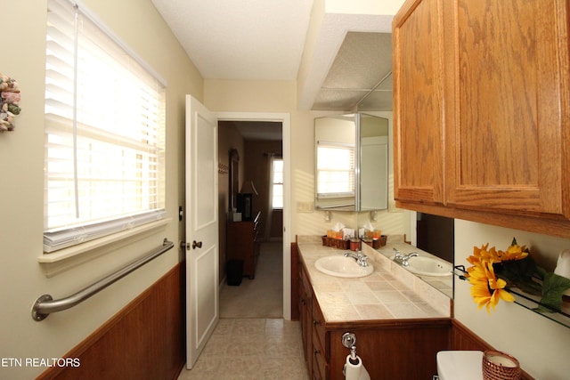 bathroom with tile patterned floors, vanity, and a healthy amount of sunlight
