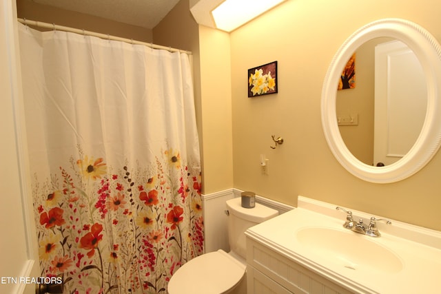 bathroom featuring a shower with curtain, wainscoting, toilet, and vanity