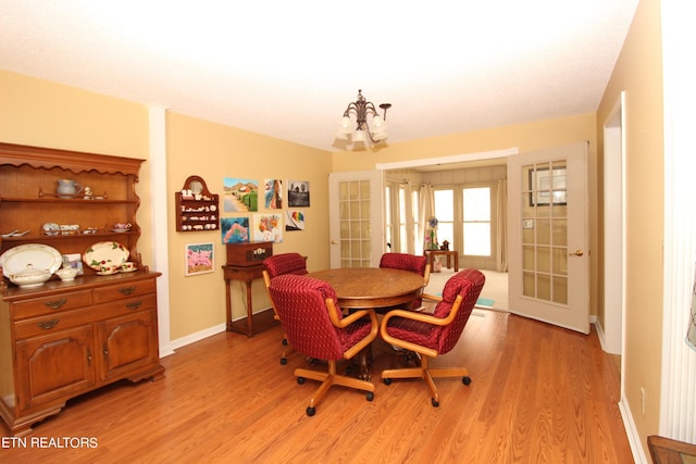 dining area with baseboards, light wood-style floors, french doors, and an inviting chandelier