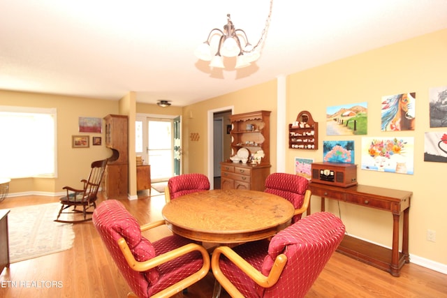 dining area with baseboards, a notable chandelier, and light wood-style floors