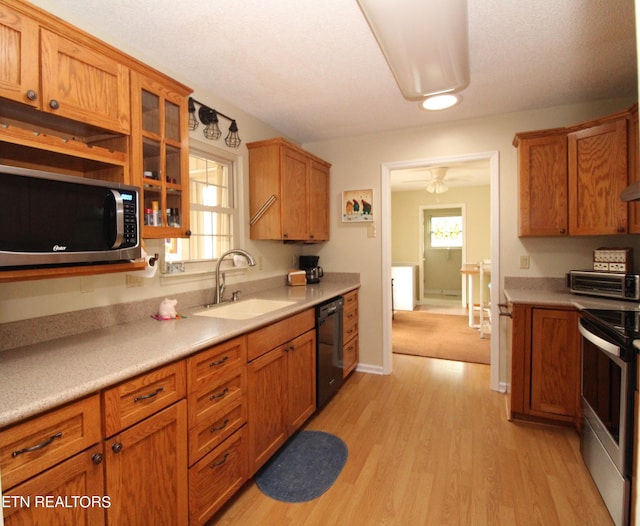 kitchen featuring light countertops, a sink, light wood-type flooring, and appliances with stainless steel finishes