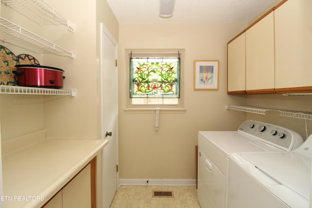 laundry area featuring washing machine and dryer, light floors, baseboards, visible vents, and cabinet space