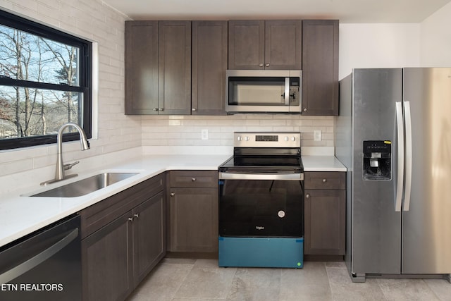 kitchen with stainless steel appliances, sink, dark brown cabinetry, and decorative backsplash