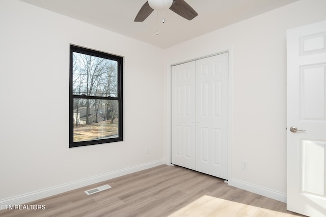 unfurnished bedroom with ceiling fan, a closet, and light wood-type flooring