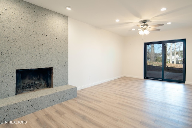 unfurnished living room featuring ceiling fan, a premium fireplace, and light hardwood / wood-style flooring