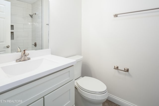 bathroom with tiled shower, vanity, and toilet