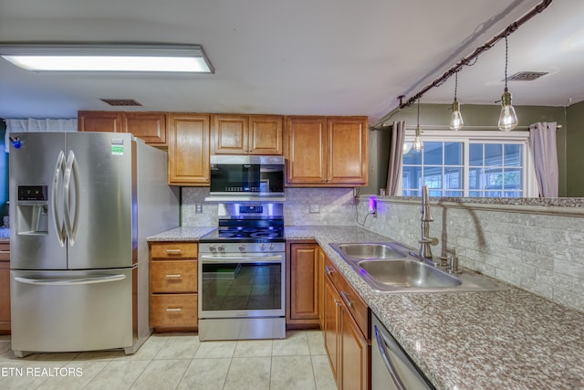 kitchen with sink, hanging light fixtures, tasteful backsplash, light tile patterned floors, and appliances with stainless steel finishes