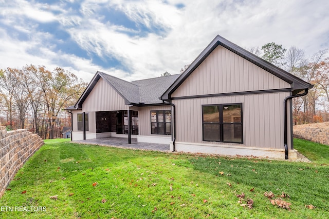 back of house with a yard, a shingled roof, and a patio