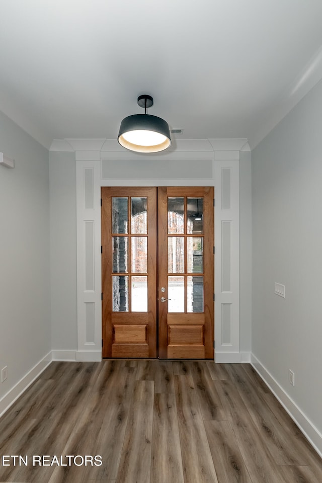 entryway with crown molding, baseboards, wood finished floors, and french doors