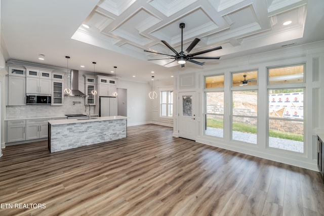 kitchen featuring coffered ceiling, a sink, freestanding refrigerator, wall chimney exhaust hood, and stainless steel microwave