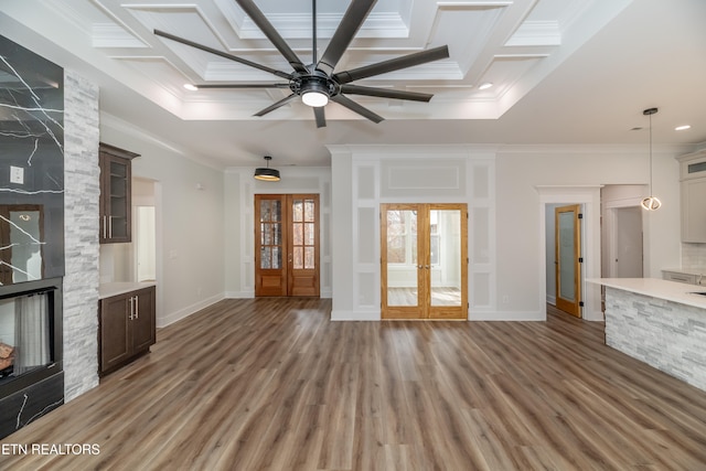 unfurnished living room with light wood finished floors, french doors, coffered ceiling, and crown molding