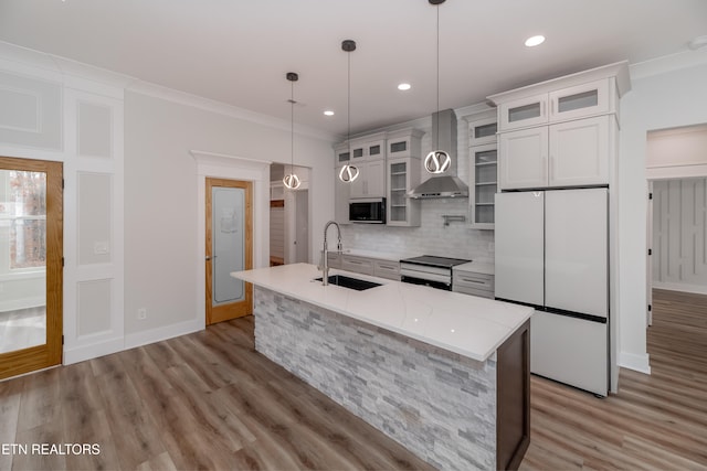 kitchen with tasteful backsplash, an island with sink, wall chimney exhaust hood, appliances with stainless steel finishes, and a sink