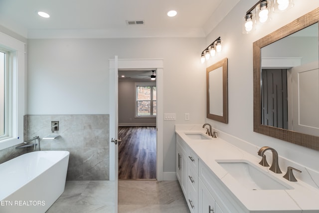 full bathroom featuring a soaking tub, a sink, tile walls, and double vanity