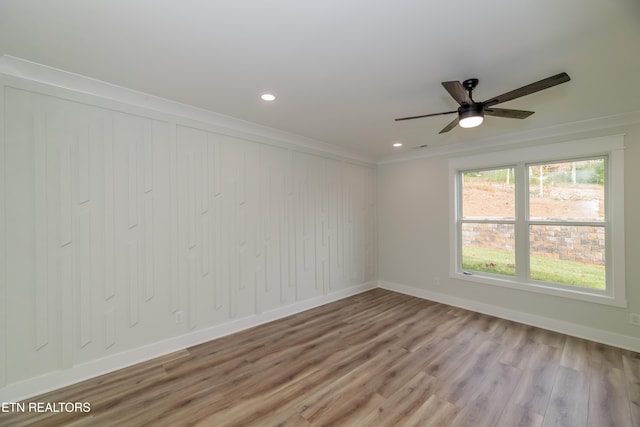 spare room with crown molding, recessed lighting, a ceiling fan, wood finished floors, and baseboards