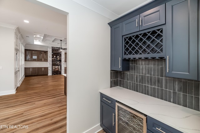 bar with decorative backsplash, wine cooler, ornamental molding, a bar, and light wood-style floors