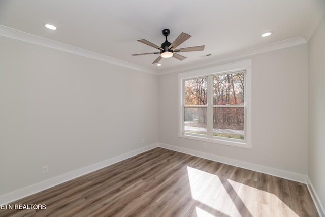 empty room featuring crown molding, recessed lighting, a ceiling fan, wood finished floors, and baseboards