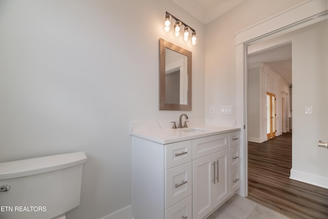 bathroom featuring baseboards, vanity, toilet, and wood finished floors