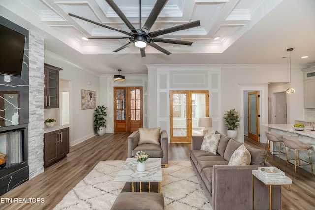 living area featuring ornamental molding, french doors, coffered ceiling, and light wood finished floors