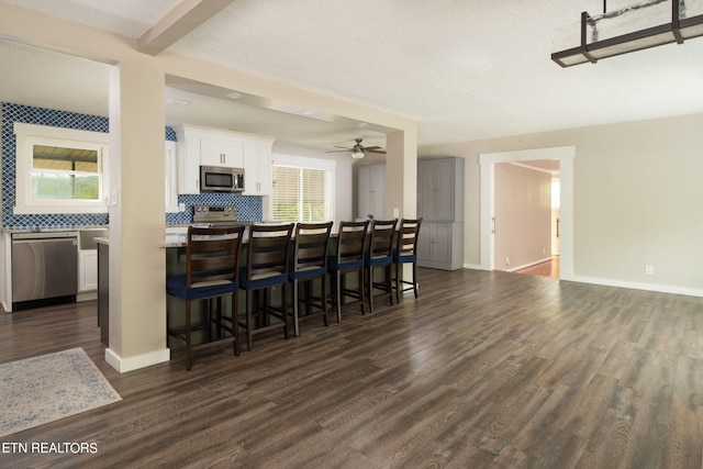 kitchen with a healthy amount of sunlight, white cabinets, appliances with stainless steel finishes, and dark wood-type flooring