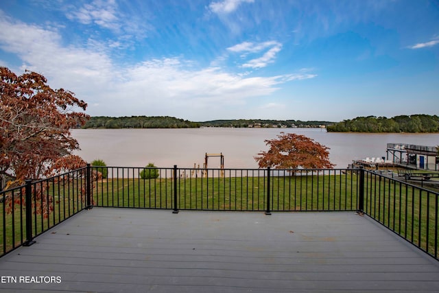 wooden terrace with a water view and a lawn