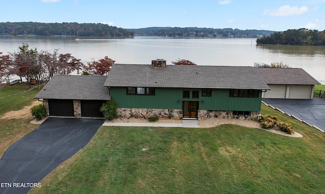 ranch-style home with a garage, a front lawn, and a water view