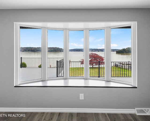 empty room with dark hardwood / wood-style floors and a water view