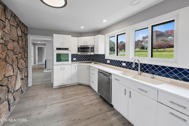 kitchen featuring light hardwood / wood-style floors, white cabinetry, tasteful backsplash, and stainless steel appliances