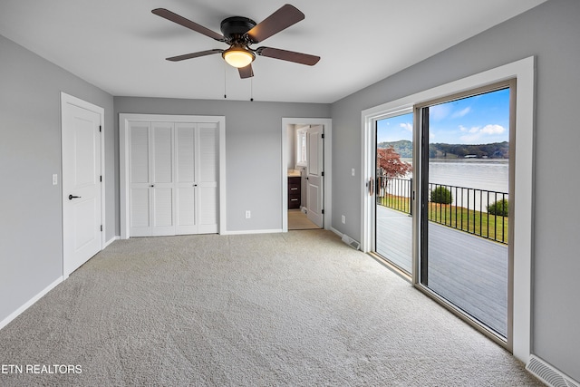 unfurnished bedroom with access to exterior, a closet, light carpet, ensuite bath, and ceiling fan