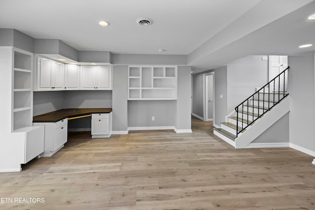 unfurnished office featuring light hardwood / wood-style floors and built in desk