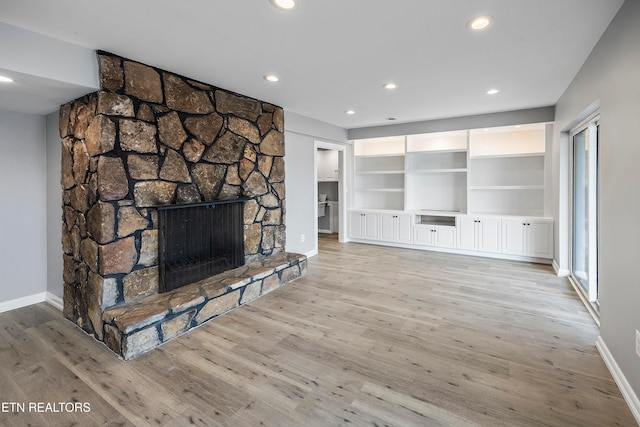 unfurnished living room with light hardwood / wood-style flooring and a stone fireplace