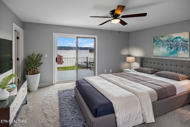 bedroom featuring access to exterior, light colored carpet, ceiling fan, and a water view