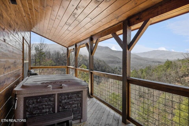 wooden deck featuring a hot tub and a mountain view