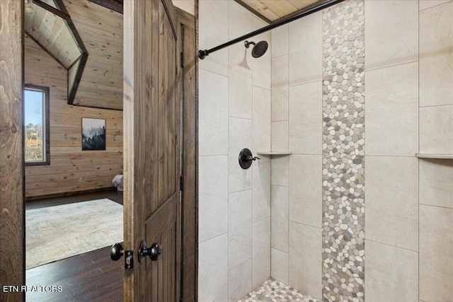 bathroom featuring wood ceiling, wood walls, hardwood / wood-style flooring, and tiled shower