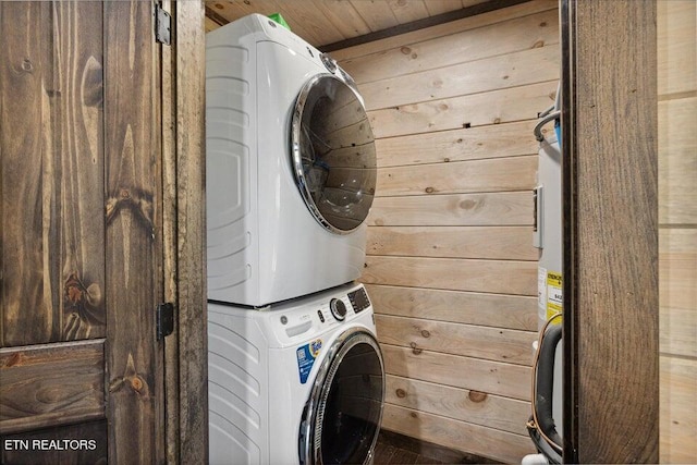 laundry area with wood ceiling, wood walls, and stacked washer and dryer