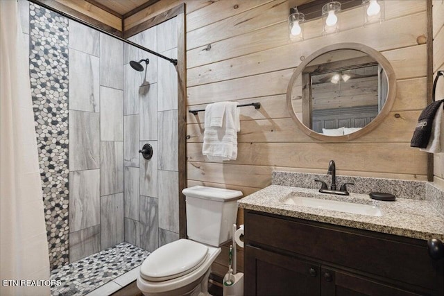 bathroom featuring a tile shower, vanity, wooden walls, and toilet