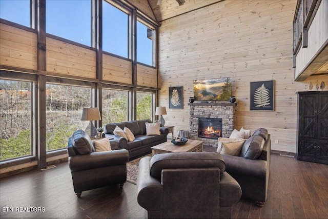 living room featuring a stone fireplace, wooden walls, dark hardwood / wood-style floors, and high vaulted ceiling