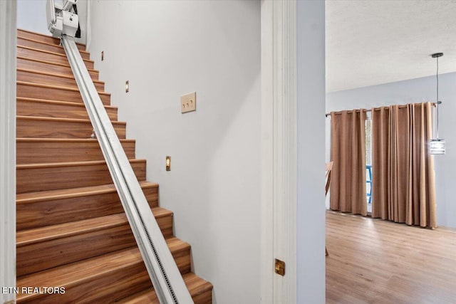 staircase with wood-type flooring and a textured ceiling