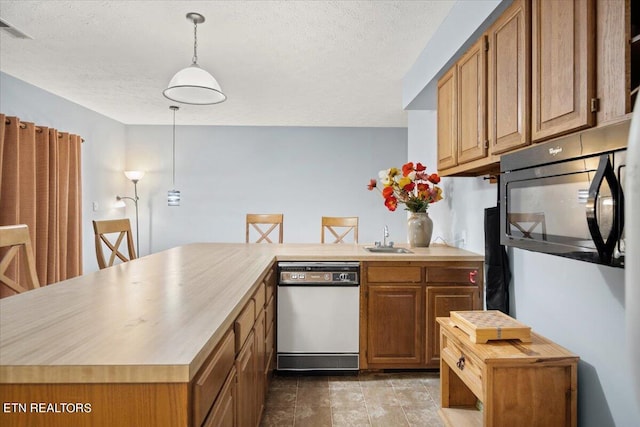 kitchen with pendant lighting, dishwasher, sink, a textured ceiling, and kitchen peninsula