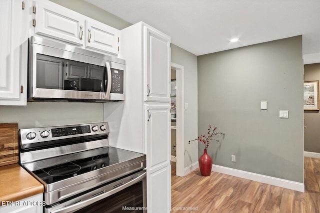 kitchen featuring white cabinets, light wood-type flooring, and appliances with stainless steel finishes