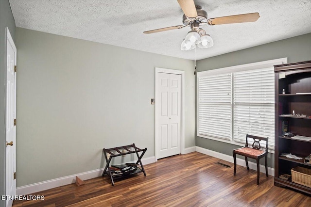 interior space featuring a textured ceiling, ceiling fan, and dark wood-type flooring