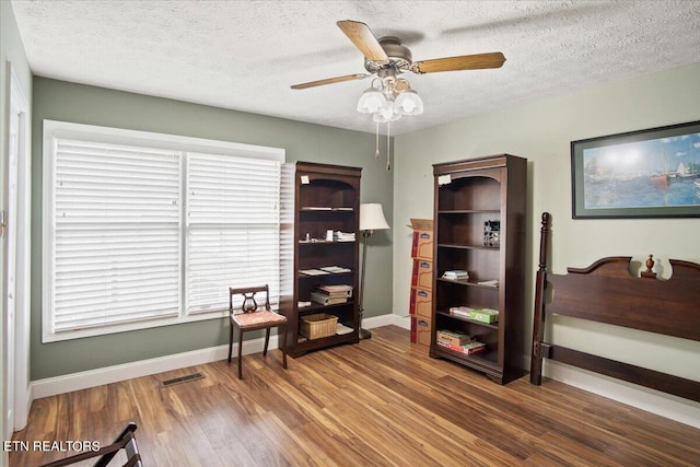 miscellaneous room featuring ceiling fan, dark hardwood / wood-style flooring, and a textured ceiling