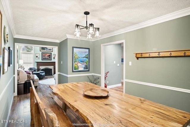 dining area with ornamental molding, wood-type flooring, a textured ceiling, and an inviting chandelier